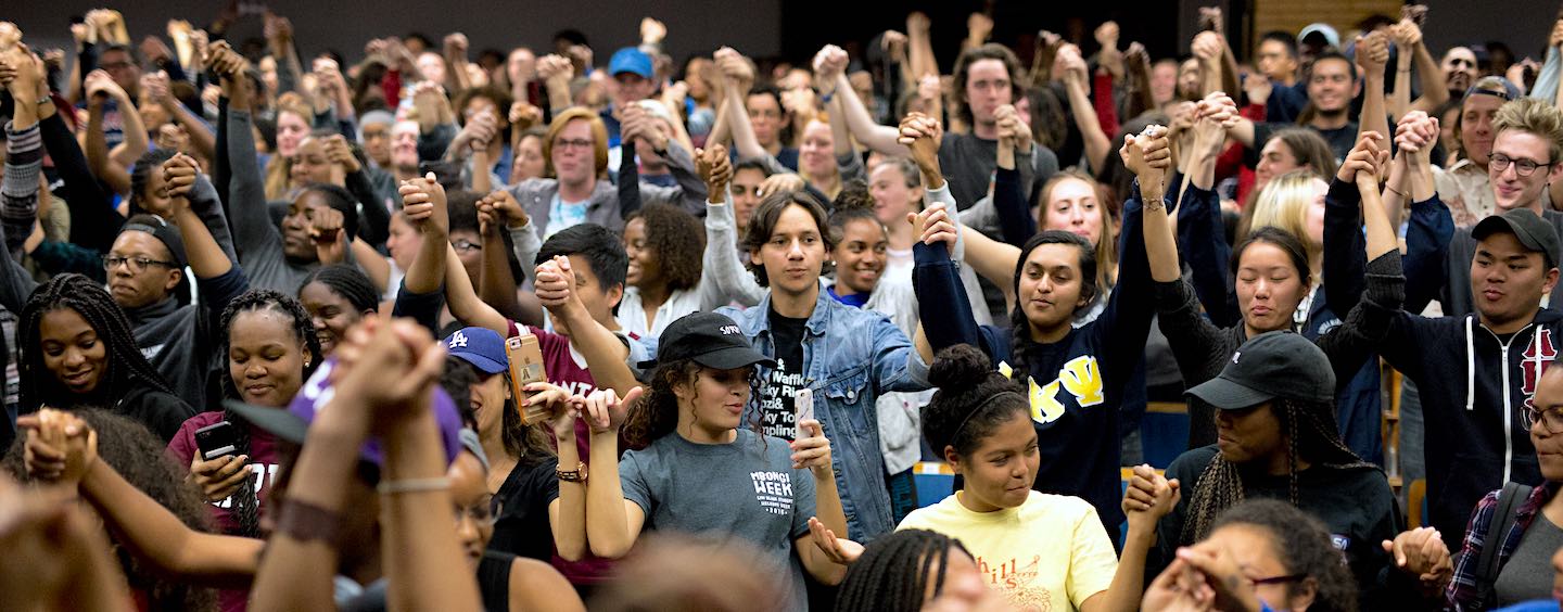 Crowd of diverse students holding raised hands in solidarity